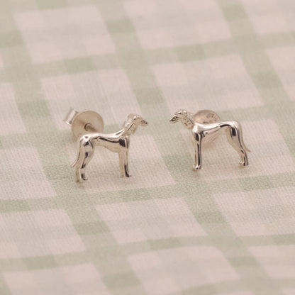 Silver dog-shaped earrings on a checkered fabric background
